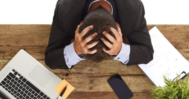 businessman sitting at office desk with hands on his head crying devastated and frustrated Die Informationsflut und ständige Erreichbarkeit überfordert die Menschen immer öfters. (c) Fotolia