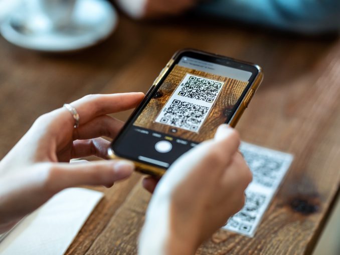 Young woman hands using the smart phone to scan the qr code to s
