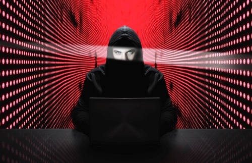 Anonymous hacker with laptop in front of binary code cyber security